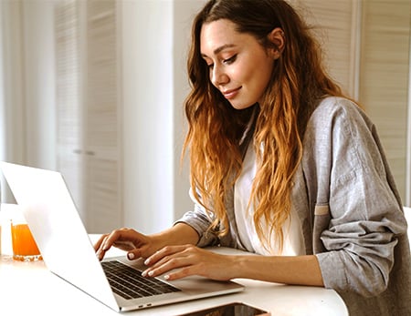 Why choose a debt consolidation loan with The AA and NatWest Boxed? A woman types on her laptop.