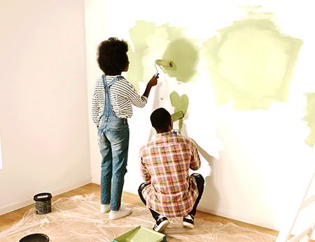 Home improvement loans A man and a woman paint a wall green.