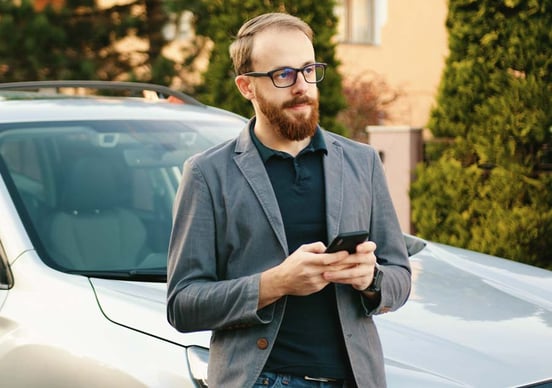 Man waits by his car Man holding his phone waiting for AA patrol outside his home