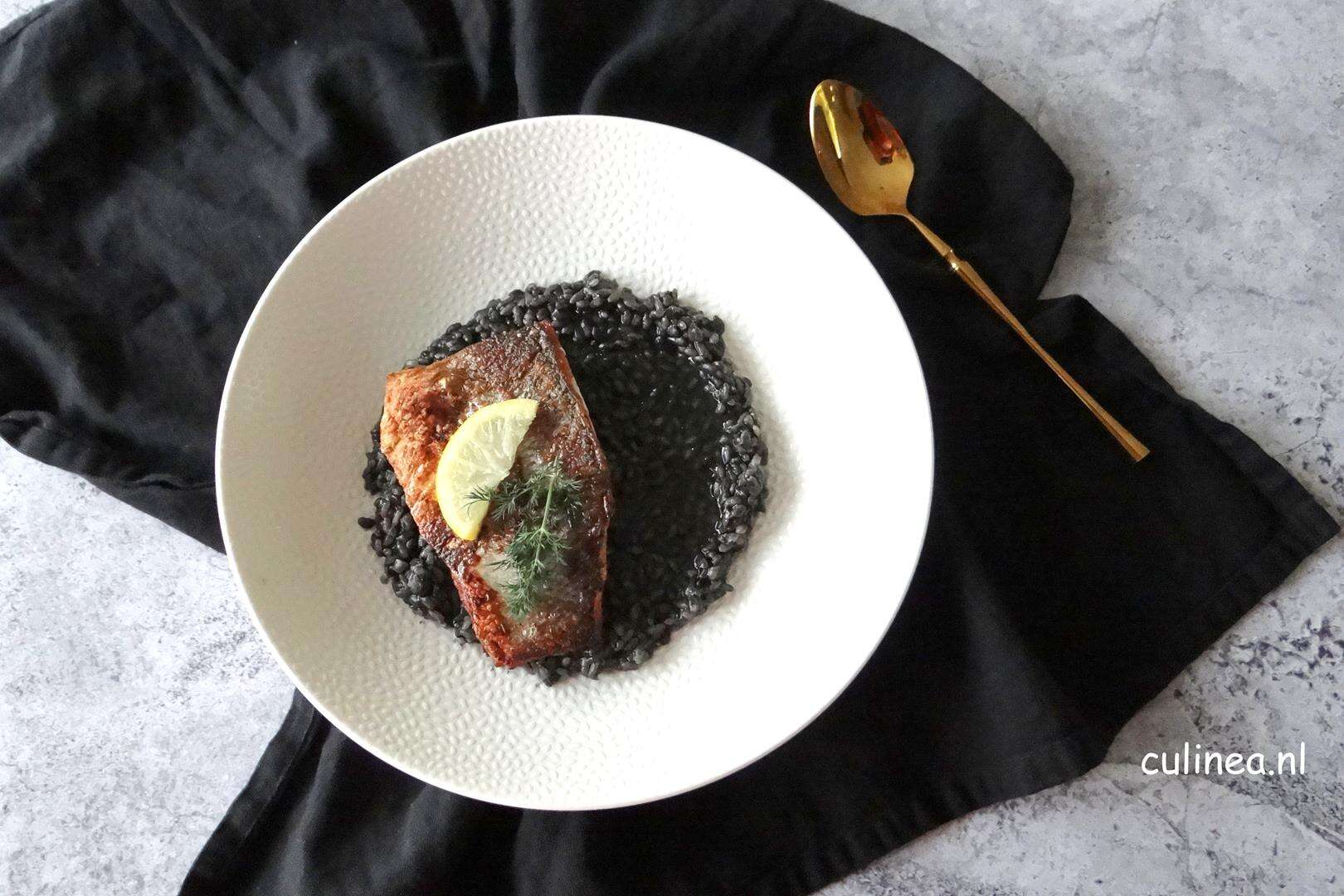 zwarte risotto met zeebaarsfilet op een bord