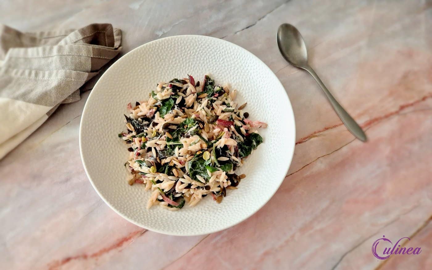 Orzo met spekjes en snijbiet op een bord