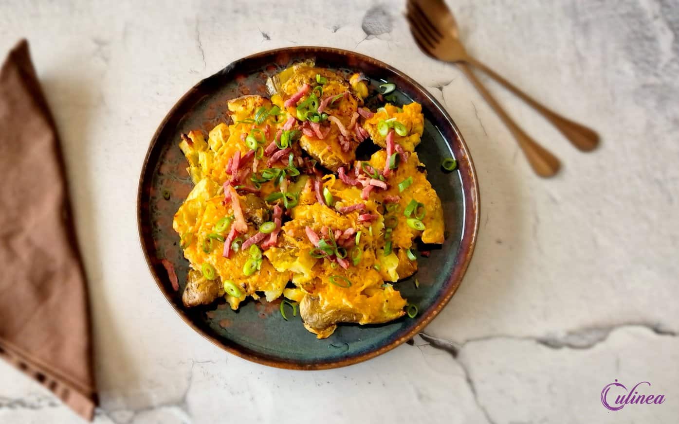 Smashed Aardappelen met kaas en spekjes op een bord